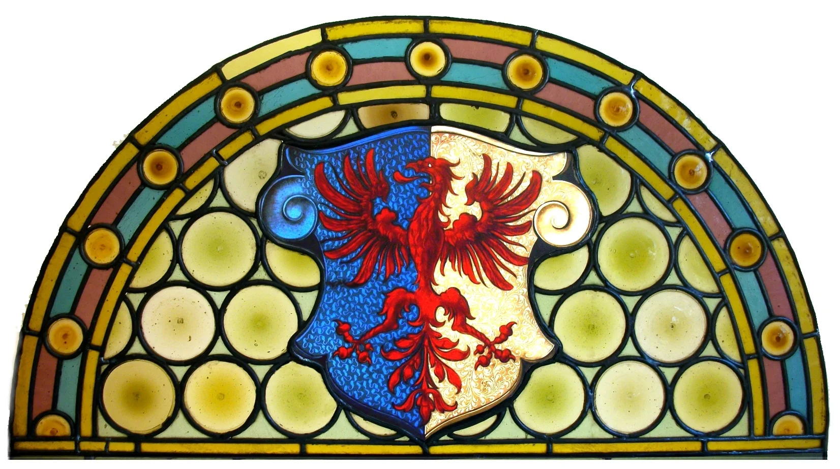 Un aigle rouge au centre d’une imposte cintrée, entouré de motifs circulaires et d’une bordure colorée.