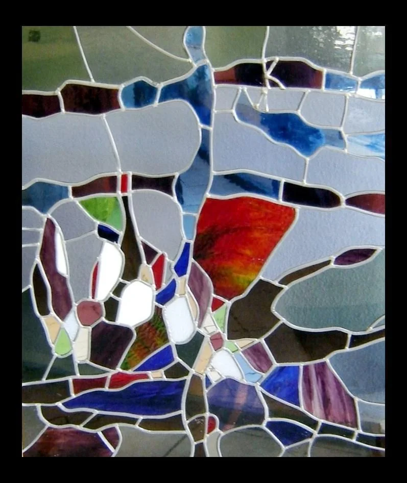 Des formes irrégulières en verre bleu, rouge et clair composent ce panneau abstrait.